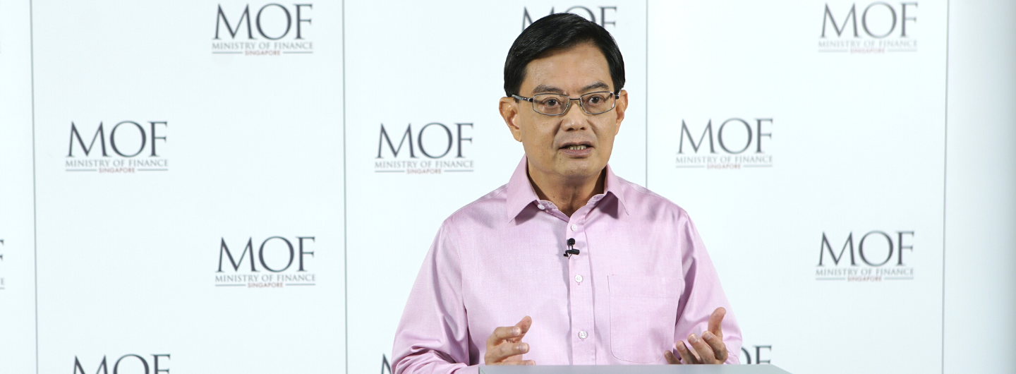 Singapore's Lawrence Wong in a pink shirt, speaking against a Ministry of Finance (MOF) backdrop.